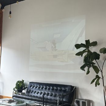 Equinox Coffee - Show projector is showing, black booth seating, plants - Coffee & Tea Near Me - Norfolk, Virginia Equinox Coffee - Show projector is showing, black booth seating, plants - Coffee & Tea Near Me - Norfolk, Virginia
