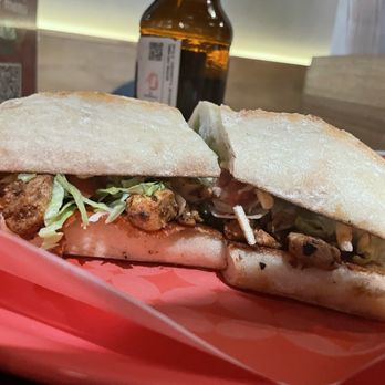 Ayayay - Tenderloin Steak Torta - A steak torta sandwich with grilled tenderloin, shredded lettuce, and bread, served on a red tray in a restaurant setting. - Mexican Near Me - Chicago, Illinois