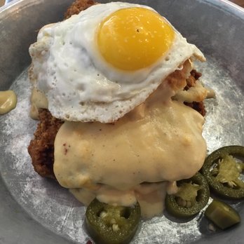 Biscuit Head - The GreenVillain A biscuit with country fried pork steak and jalapeño cream cheese topped with bacon gravy, a sunny side egg, and pickled ja - Breakfast & Brunch Near Me - Greenville, South Carolina