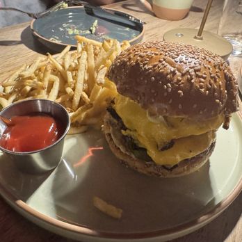 Osa Rooftop - OSA burger - A cheeseburger with melted cheese, lettuce, and a sesame seed bun is served with French fries and ketchup on a plate. - Bars Near Me - Pasadena, California