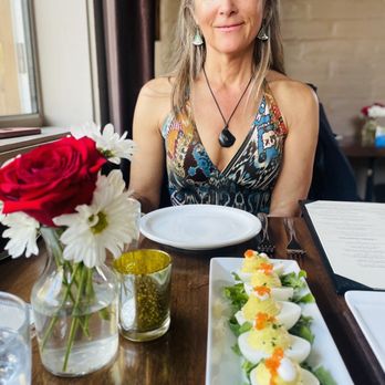 ROUX - a woman sitting at a table with a plate of deviled eggs - Tapas/Small Plates Near Me - Carmel Valley, California