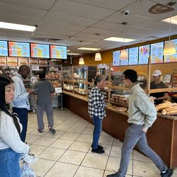 The inside of the bakery with bánh mì menu on screens above the counter