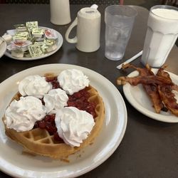 HiWay Restaurant - Belgian waffle with cherries and whipped cream with a side of bacon and a milk.