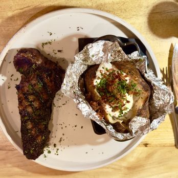 The Still Whiskey Steaks - New York Strip, so tender and full of flavor, with a huge "loaded" baked potato! - Steakhouses Near Me - Fort Collins, Colorado The Still Whiskey Steaks - New York Strip, so tender and full of flavor, with a huge "loaded" baked potato! - Steakhouses Near Me - Fort Collins, Colorado
