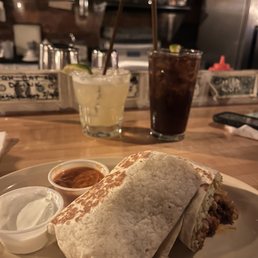 a burrito on a plate with a side of condiments a burrito on a plate with a side of condiments