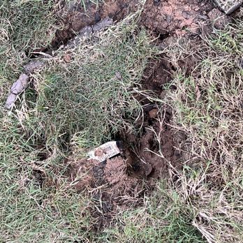 Grace Landscaping and Tree Service - "Drainage". The head of an open pipe with a piece of sod over the top. - Landscaping Near Me