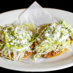 Taqueria Guerrero - Crispy fried corn tortillas layered with refried beans, your choice of meat, fresh lettuce, creamy avocado sauce, crema, and crumble cheese