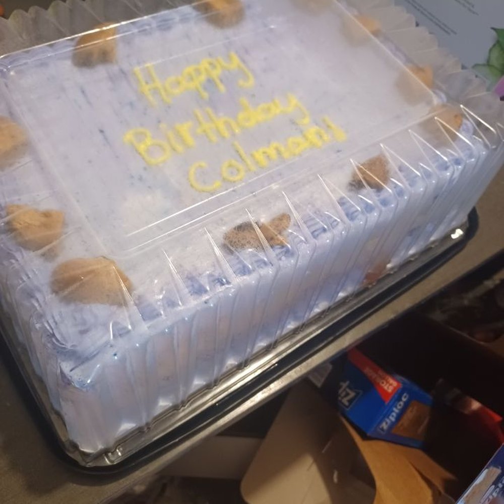 Birthday cake with a mess of paper and boxes from all the presents under it