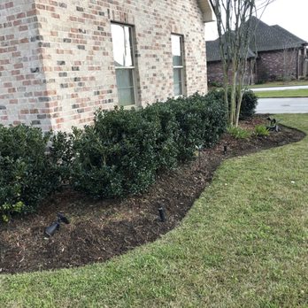 Short Blade Lawncare - a brick house with a shrub bed in front of it - Lawn Services Near Me