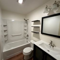 Level and Plumb Construction - Full bathroom remodel with tub/shower surround installation, new toilet, shelves, vanity, mirror, bath fan, flooring and more.