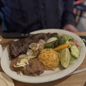 Los Arcos - Carne Asada - A plate featuring grilled meat, rice, and a side salad with cucumbers, lime, and peppers, served at a Mexican restaurant. - Tacos Near Me - Chicago, Illinois