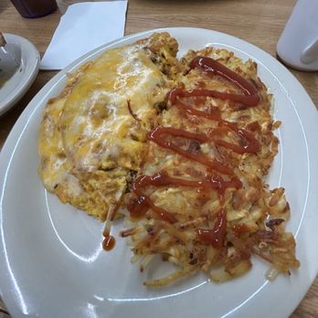 Cappy's Breakfast Cafe - A breakfast plate features hash browns with cheese and an omelette topped with ketchup, on a white oval plate at a restaurant. - Breakfast & Brunch Near Me - Tucson, Arizona