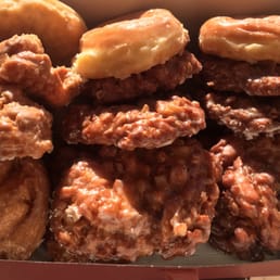 Box of apple fritters, buttermilk glaze and glazed donuts. Box of apple fritters, buttermilk glaze and glazed donuts.