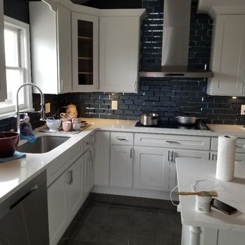 Richie Homes - a kitchen with white cabinets and a black tile backsplash - General Contractors Near Me Richie Homes - a kitchen with white cabinets and a black tile backsplash - General Contractors Near Me