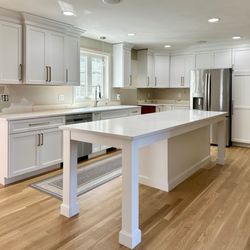 Ideal Home Improvement - A modern kitchen featuring newly refaced white cabinets and a custom-built center island.