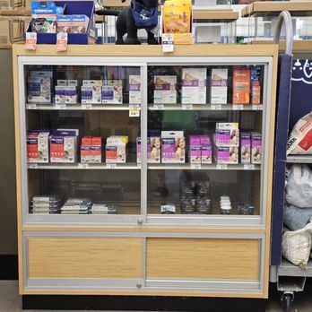 Petco - A glass-fronted display case at Petco in Cedar Park, TX, contains various pet medications and health products, with a plush dog wearing a crown on top. - Pet Training Near Me - Cedar Park, Texas