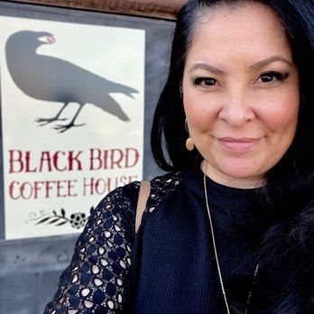 Blackbird Coffee House - A woman with dark hair and earrings is taking a selfie outside Black Bird Coffee House in Albuquerque, NM, with the business sign visible in the background. - Coffee & Tea Near Me - Albuquerque, New Mexico