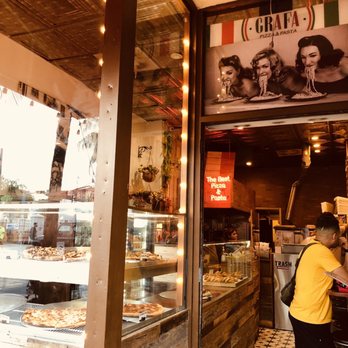 Grafa Pizza - a man standing in front of a window - Pizza Near Me - Miami Beach, Florida