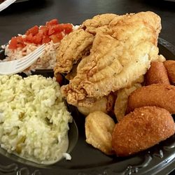 Fish House - Fried flounder sitting on top of fried shrimp with fried hush puppies and coleslaw and rice and tomatoes and a plastic fork