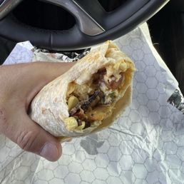 Breakfast burrito with bacon, potatoes, eggs and cheese and corn. The side sauce completes it for sure!