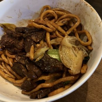 Woon - Beef noodles (half eaten) - A bowl containing beef, noodles, and vegetables such as onions and green onions, with sauce remnants on the sides. - Chinese Near Me - Pasadena, California