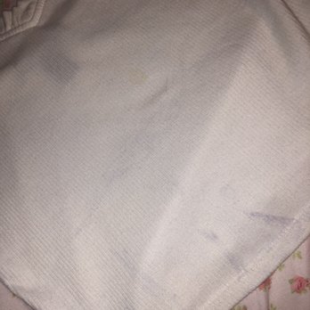 Uptown Cheapskate - More stains - A photograph shows a white fabric with visible stains and a textured pattern, placed on a floral-patterned surface. - Used, Vintage & Consignment Near Me - Apex, North Carolina