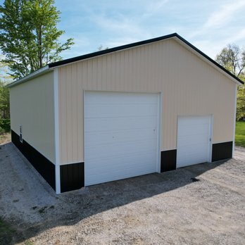 Stately Builders - Front view of cream and black pole barn garage with dual overhead doors, surrounded by trees in Amherst NY. - General Contractors Near Me - Clarence Center, New York