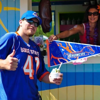 Tiki's Shave Ice - a man in a blue jersey holding a blue and orange flag - Desserts Near Me Tiki's Shave Ice - a man in a blue jersey holding a blue and orange flag - Desserts Near Me