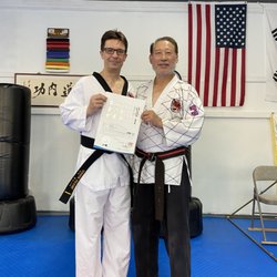 Kimoo Martial Arts - Student receiving black belt promotion certificate.