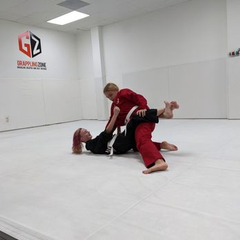 Grappling Zone - two teens doing Brazilian Jiu-jitsu on a mat in a dojo at Grappling Zone Friendswood - Self-defense Classes Near Me - Friendswood, Texas