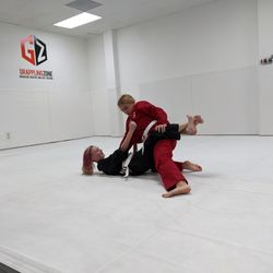 Grappling Zone - Two teens doing Brazilian Jiu-jitsu on a mat in a dojo at Grappling Zone Friendswood