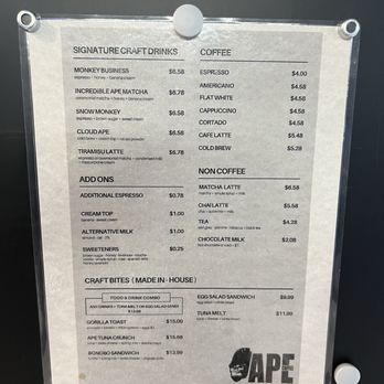 Ape Coffee - A printed menu board from Ape Coffee in Placentia, CA, listing coffee drinks, craft bites, and add-ons with prices, mounted on a wall. - Cafes Near Me - Placentia, California