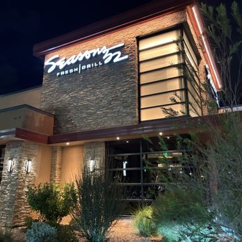 Seasons 52 - Restaurant front - Exterior of Seasons 52 restaurant at night, featuring a lit sign, stone accents, and modern design elements with landscaping. - New American Near Me - Albuquerque, New Mexico