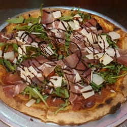 Comics Pizza - La Specktaculaire : sauce tomate, tomates cerise marinées, après cuisson: moza di bufala, speck, roquette, parmesan, crème balsamique.