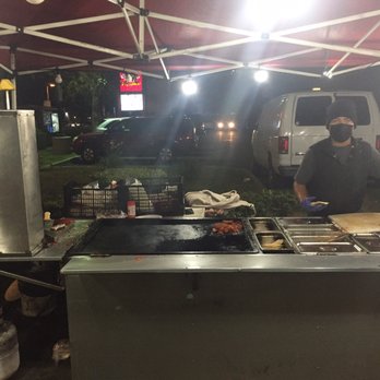 Tacos El Travieso - a man preparing food under a tent - Tacos Near Me Tacos El Travieso - a man preparing food under a tent - Tacos Near Me