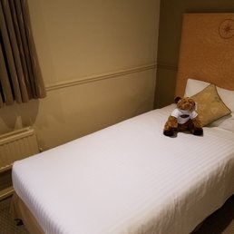 Tiny little bed with a teddy bear on it.