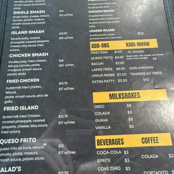 Between Two Buns - A menu board from a food truck lists various burgers, loaded fries, milkshakes, and drinks with prices, set outdoors. - Burgers Near Me - Miami, Florida