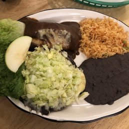 Combinacion Sarape with Tostadas and Enchiladas Poblanos - A Mexican dish featuring rice, shredded lettuce, a slice of apple, and two enchiladas with dark sauce, served on a white plate.