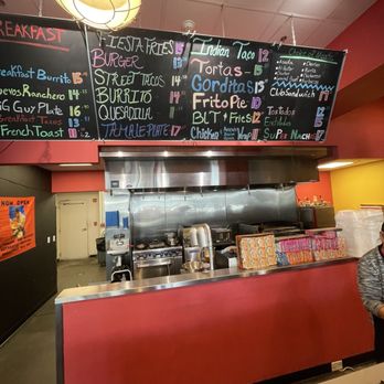 La Zenita - Order counter - A restaurant counter with a black menu board displaying various Mexican dishes and prices, including tacos, burritos, and quesadillas, with a kitchen area behind. - Mexican Near Me - Albuquerque, New Mexico