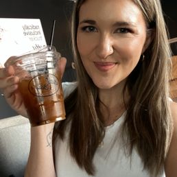Rebekah holds an iced coffee displaying the Bitty and Beau's logo on the cup