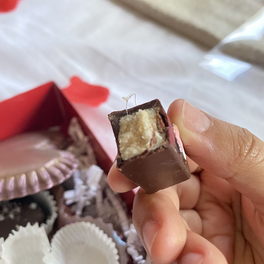 Quintessential Chocolates - a hand holding a piece of chocolate - Candy Stores Near Me - Fredericksburg, Texas Quintessential Chocolates - a hand holding a piece of chocolate - Candy Stores Near Me - Fredericksburg, Texas