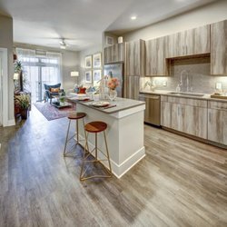 Arise Riverside Apartments - A kitchen with a white island and wooden cabinets.