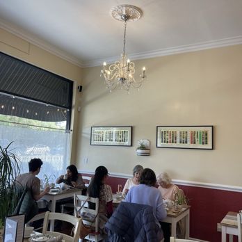 A modern cafe setting with people enjoying various Honeybush tea-based beverages and snacks