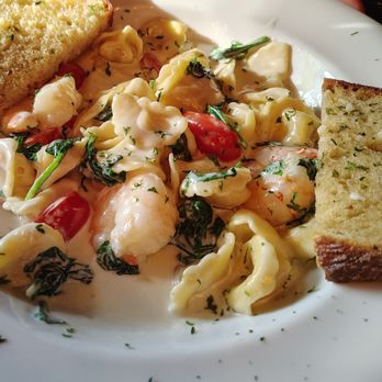 Tangled Garden 2.0 - Tortellini gorgonzola - A close-up of a plate containing tortellini pasta coated in a creamy gorgonzola cheese sauce, garnished with chopped herbs. The dish includes cherry tomatoes and spinach, with two slices of toasted garlic bread on the side. The presentation emphasizes the pasta and bread, highlighting the creamy texture and fresh ingredients. - American Near Me - Perth, Ontario