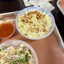 Potato salad and coleslaw. Food is served on cute trays with paper on them. Potato salad and coleslaw. Food is served on cute trays with paper on them.