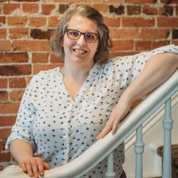 Jocelyn Buitenhuis, RMT - Photo of Jocelyn on a white staircase with red brick behind her.