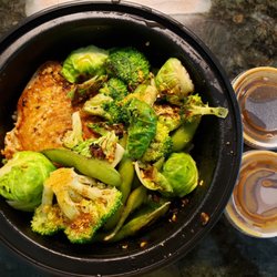 Small bowl with salmon and veggies. Sauces on the side