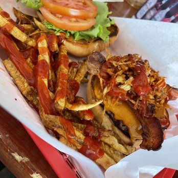 Bob Dobbs - A burger with tomato slices, lettuce, and onion on a bun, accompanied by fries topped with ketchup and crispy fried onions. - Bars Near Me - Tucson, Arizona