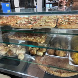 a variety of pizzas in a display case