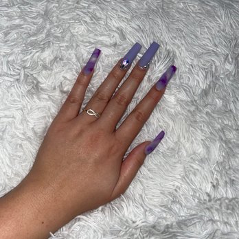 Century Nails - A hand with long, decorated nails featuring purple and gray designs is placed on a white, textured, furry surface. - Nail Salons Near Me - Phoenix, Arizona